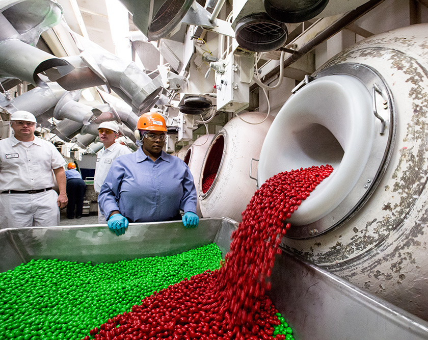 Workers check red and green M&Ms being produced in a factory.