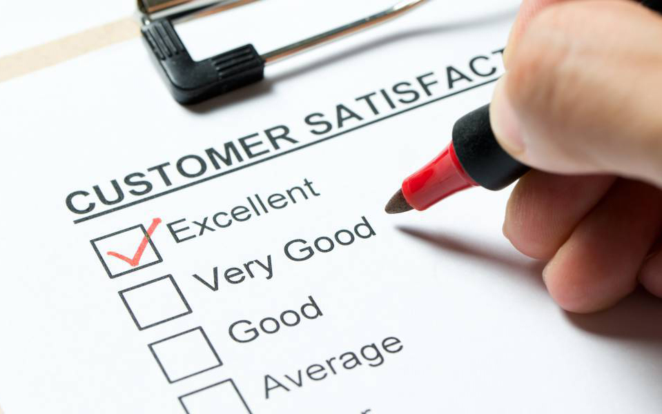 A person fills out a customer satisfaction survey with a red pen.