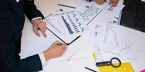 Two people sit at a desk looking over financial documents.