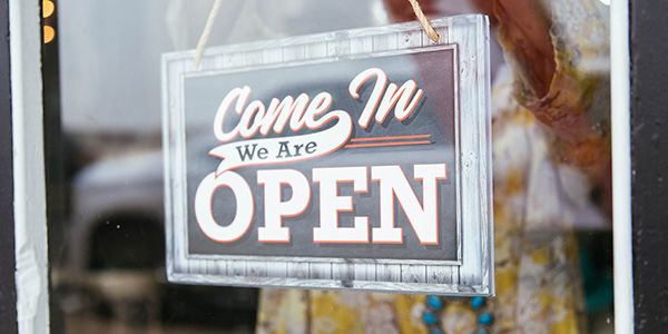 A woman hangs an OPEN sign in a window.