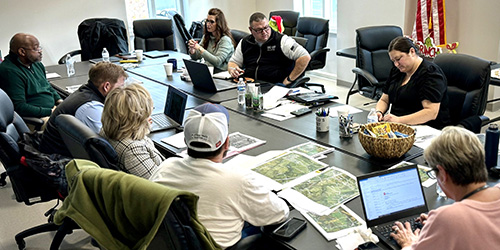 A group of people sit around a large conference table in discussion.